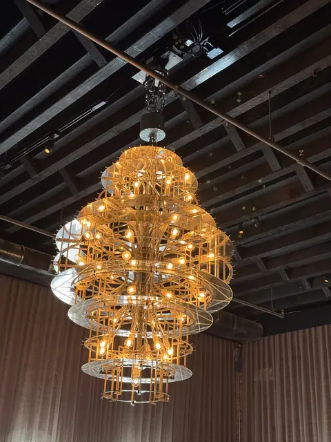 Tiered gold chandelier under an exposed ceiling
